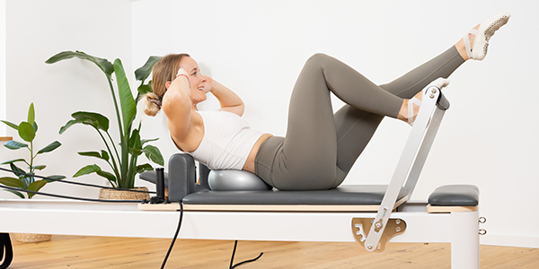 Eine Person macht auf dem Reformer Bauchübungen.