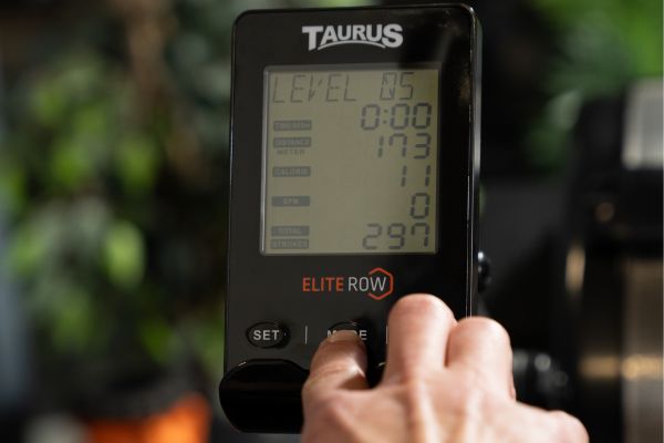 Nahaufnahme der Konsole des Taurus Elite Rower, auf der eine Person Einstellungen vornimmt.