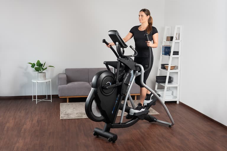 Eine Person trainiert in Sportbekleidung in wohnlicher Umgebung auf einem cardiostrong Crosstrainer.