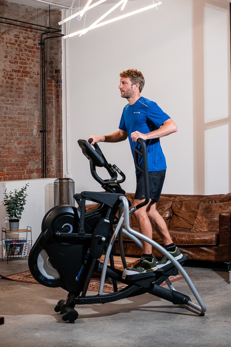 Eine Person trainiert in Sportbekleidung in wohnlicher Umgebung auf einem cardiostrong Crosstrainer.