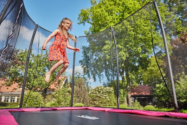 Kind springt auf einem Trampolin im Garten.