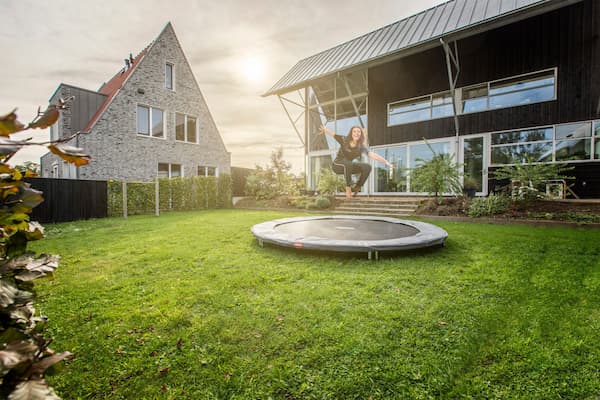 Erwachsene Person springt auf einem Inground Trampolin in einem Garten.