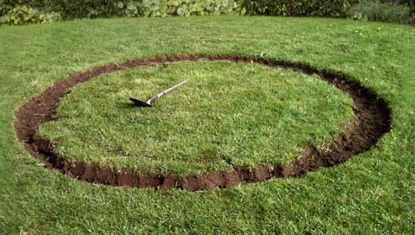 In einem Garten wurde auf dem Rasen ein kreisf&ouml;rmiger Aushub vorgenommen, in der Mitte liegt eine Schaufel.