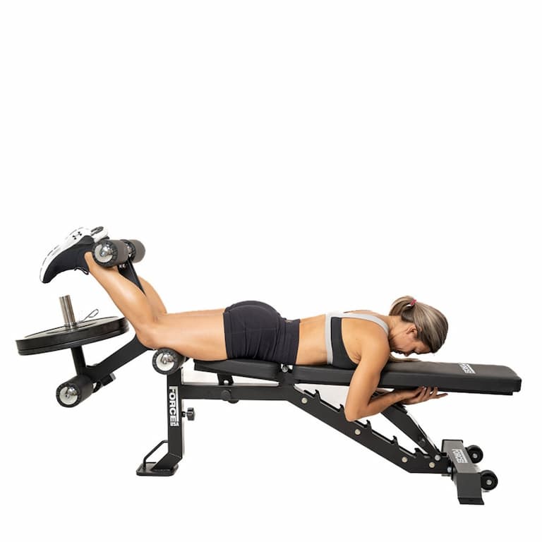 Person in sportlicher Kleidung führt eine Beincurl-Übung an der Force USA Hantelbank MyBench FID aus.