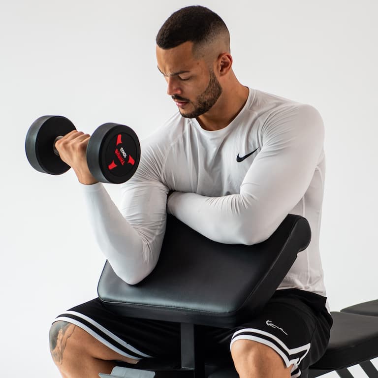 Person führt Bizeps-Curls an einem Curl-Pult aus.