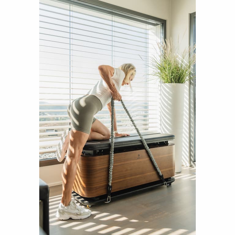 Person in Sportbekleidung trainiert auf der auf der NOHRD StepBox mit einem Widerstandsband.