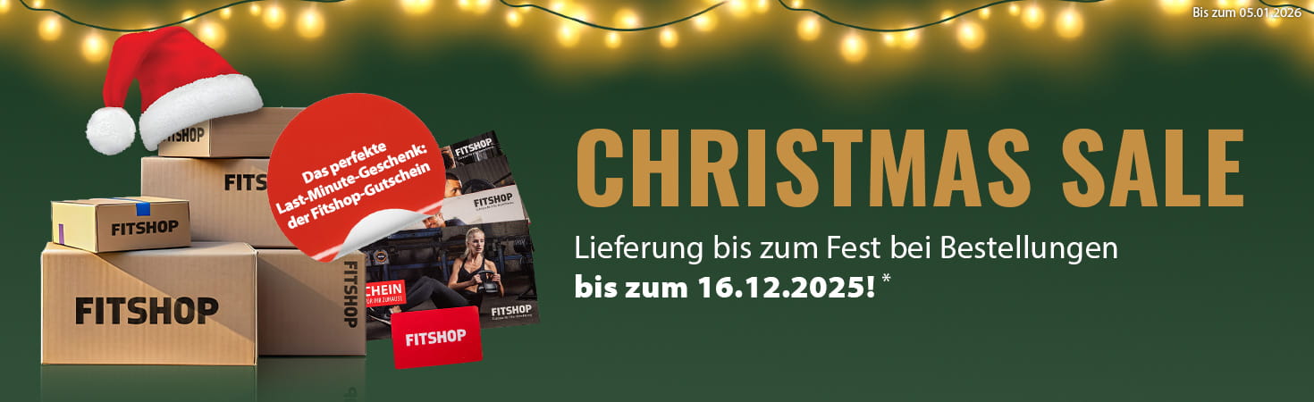 Ein weihnachtlicher Werbebanner mit grünem Hintergrund und einer Lichterkette am oberen Bildrand. Auf der linken Seite liegen mehrere Pakete mit der Aufschrift „Fitshop“. Daneben sind mehrere Fitshop-Geschenkgutscheine abgebildet. In einem rot hervorgehobenen Textfeld steht „Das perfekte Last-Minute-Geschenk: der Fitshop-Gutschein“. Auf der rechten Seite steht in Großbuchstaben „Christmas Sale“ sowie der Zusatz „Lieferung bis zum Fest bei Bestellungen bis zum 16.12.2025!“.