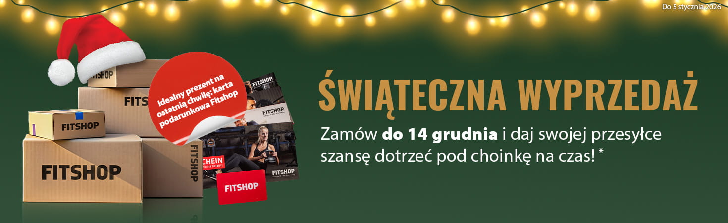 Świąteczny baner z zielonym tłem i girlandą świateł u góry. Po lewej stronie znajdują się paczki z logo „Fitshop”, obok widoczne są karty podarunkowe Fitshop. W czerwonym polu widnieje napis: „Idealny prezent na ostatnią chwilę: karta podarunkowa Fitshop”. Po prawej stronie duży napis „Christmas Sale” oraz dopisek: „Dostawa przed Świętami dla zamówień złożonych do 14.12.2025!”