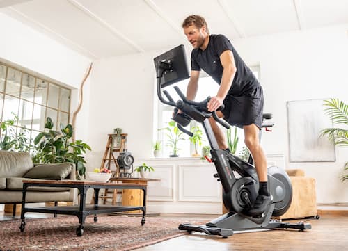 Ein Mann trainiert im Wohnzimmer auf einem Indoor Bike