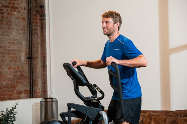 Mann mit blauem T-Shirt trainiert auf einem Crosstrainer