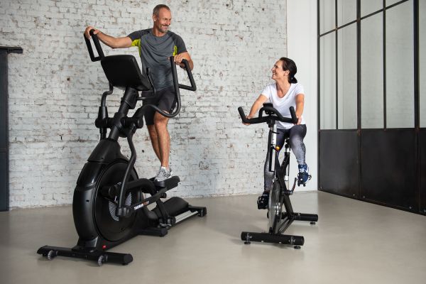 Ein Mann trainiert auf einem Crosstrainer und eine Frau auf einem Indoor-Bike