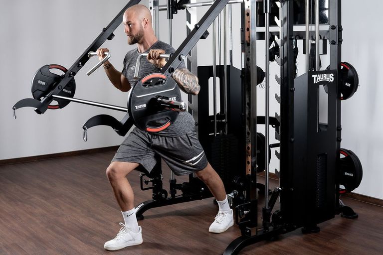 Eine Person trainiert mit den Jammer Arms einer Kraftstation. Die Jammer Arms sind mit Scheibengewichten beladen.