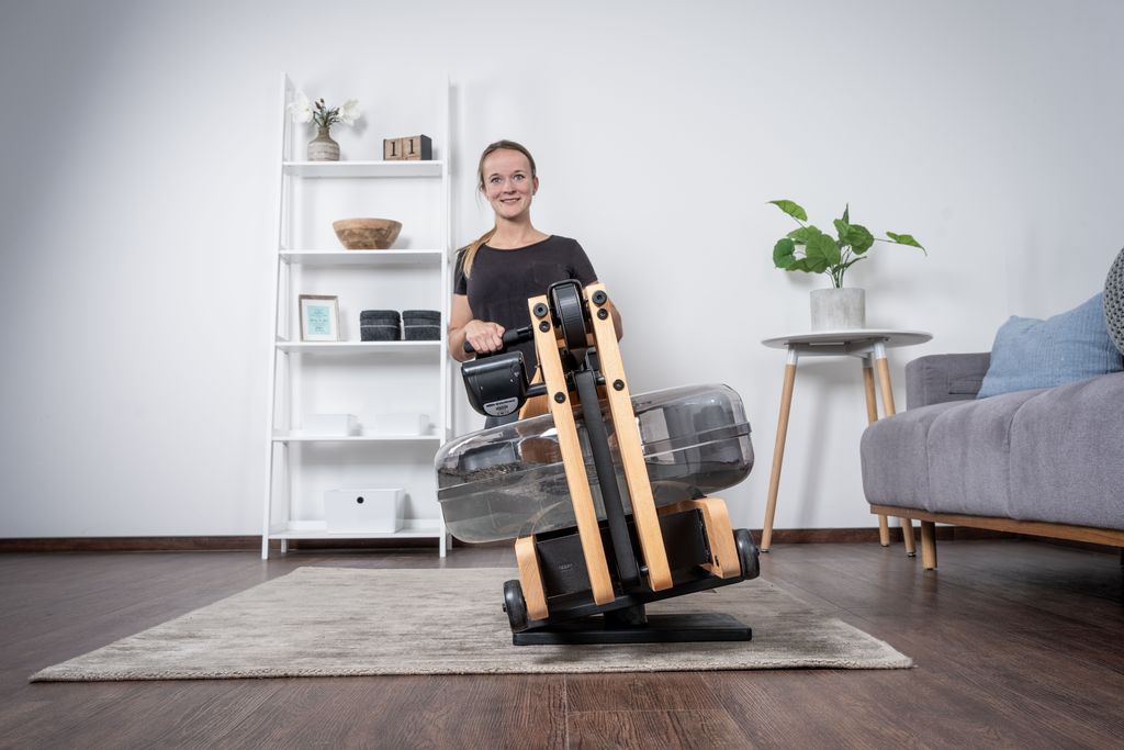 Frau trainiert auf einem Rudergerät mit dem Balance Board, wodurch das Rudergerät zur Seite kippt.