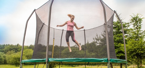 Une fillette saute sur un trampoline entouré d'un filet de sécurité.