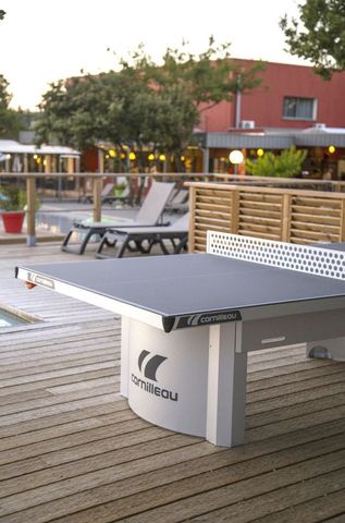 Une table de ping-pong d'extérieur avec une structure stable est installée dans un lieu public.