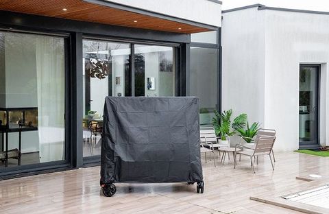 Une table de ping-pong sur une terrasse est protégée par une housse de protection