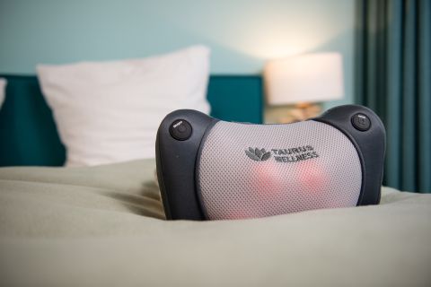 Représentation du produit du coussin de massage Taurus Wellness posé sur un lit.