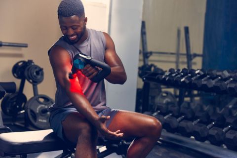 Un homme en tenue de sport profite d'un moment de détente avec le pistolet de massage Theragun Pro Plus.